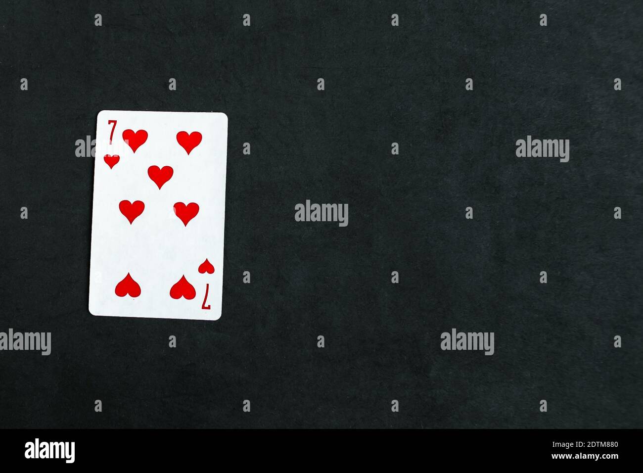 Seven of Hearts playing card, black background, copy space Stock Photo