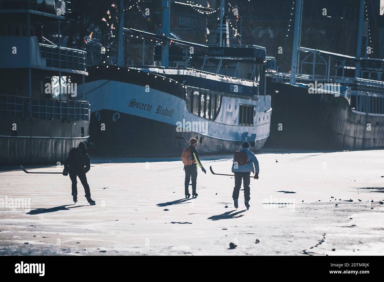 Three boys play ice hockey on the frozen Aura River in Turku, Finland Stock Photo