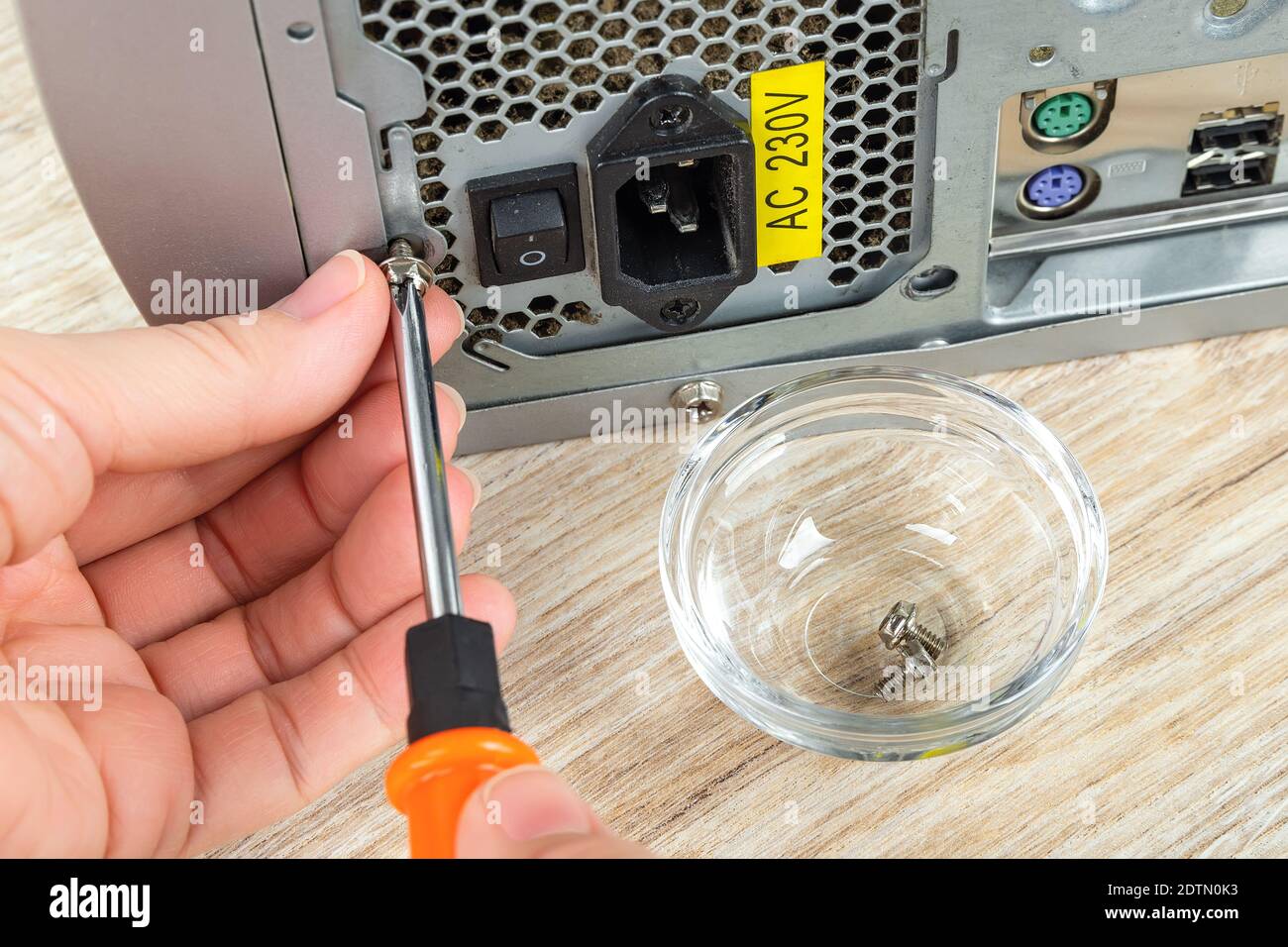 Woman hands remove the screw holding old power supply unit in a tower ...