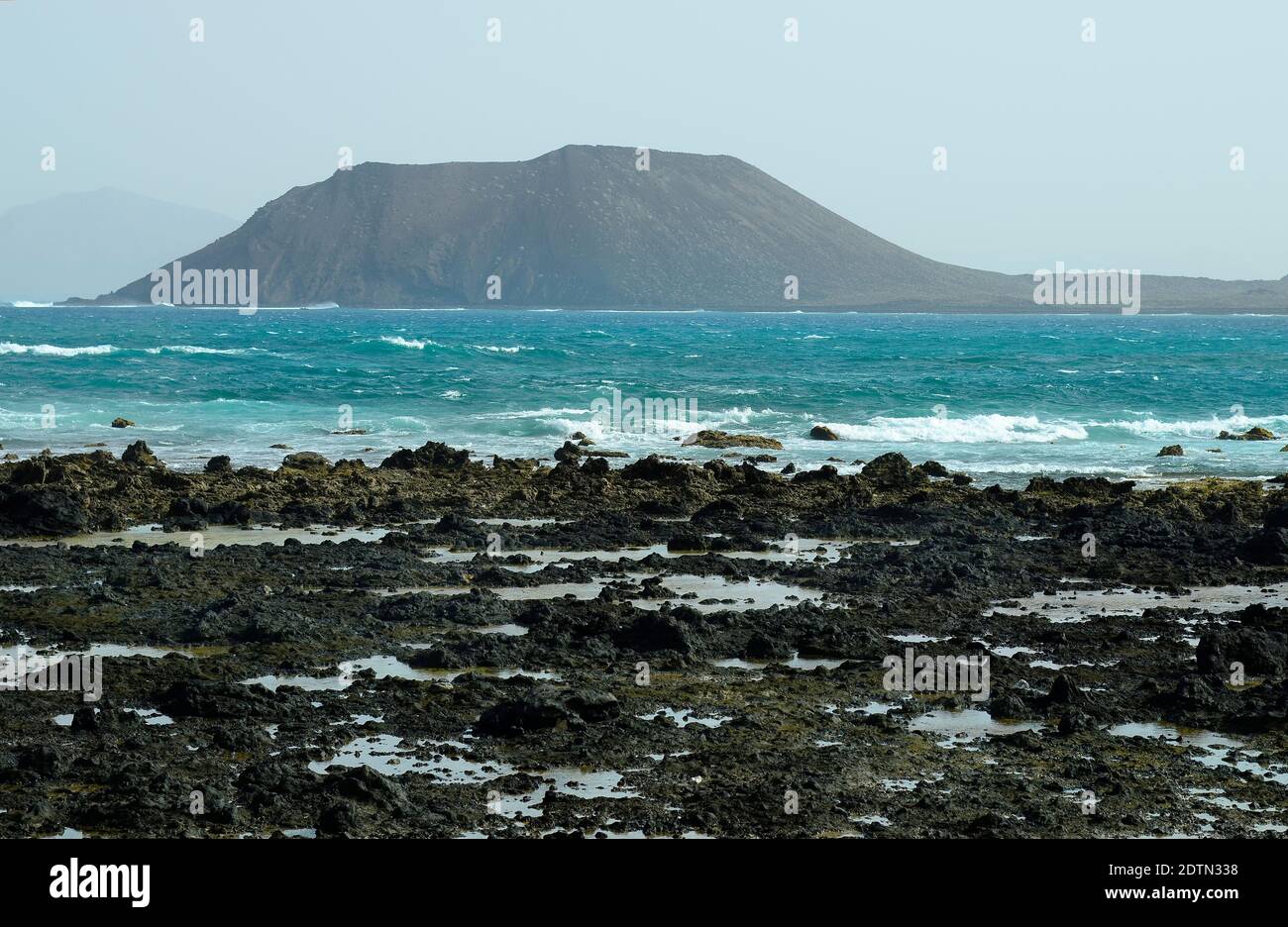 Spain, Canary Island, Fuerteventura, rocky coast with Los Lobos island behind Stock Photo