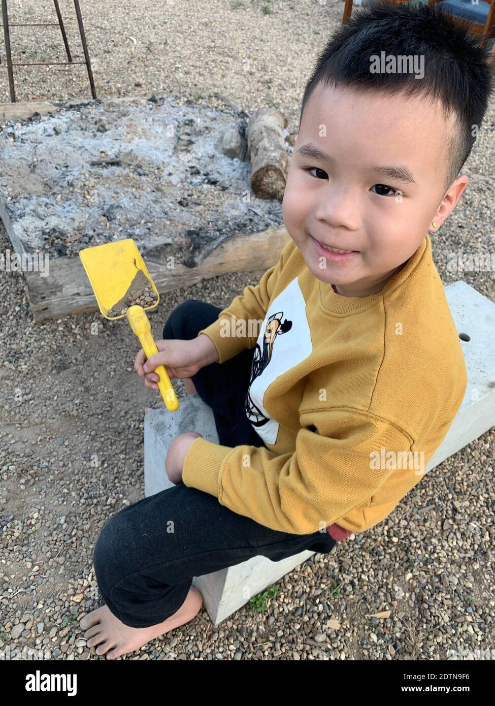 Portrait Of Boy Holding Yellow While Sitting Outdoors Stock Photo