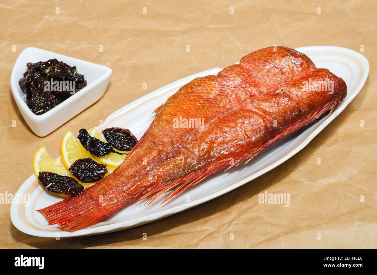 Hot smoked sea bass with lemon and dried spicy plums, closeup on a