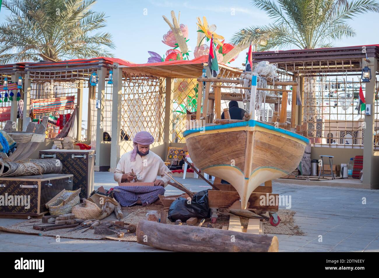 Arabic fisherman, repairing home-made fishing net and wooden yacht, wearing face mask and sits on the floor of traditional boam Stock Photo