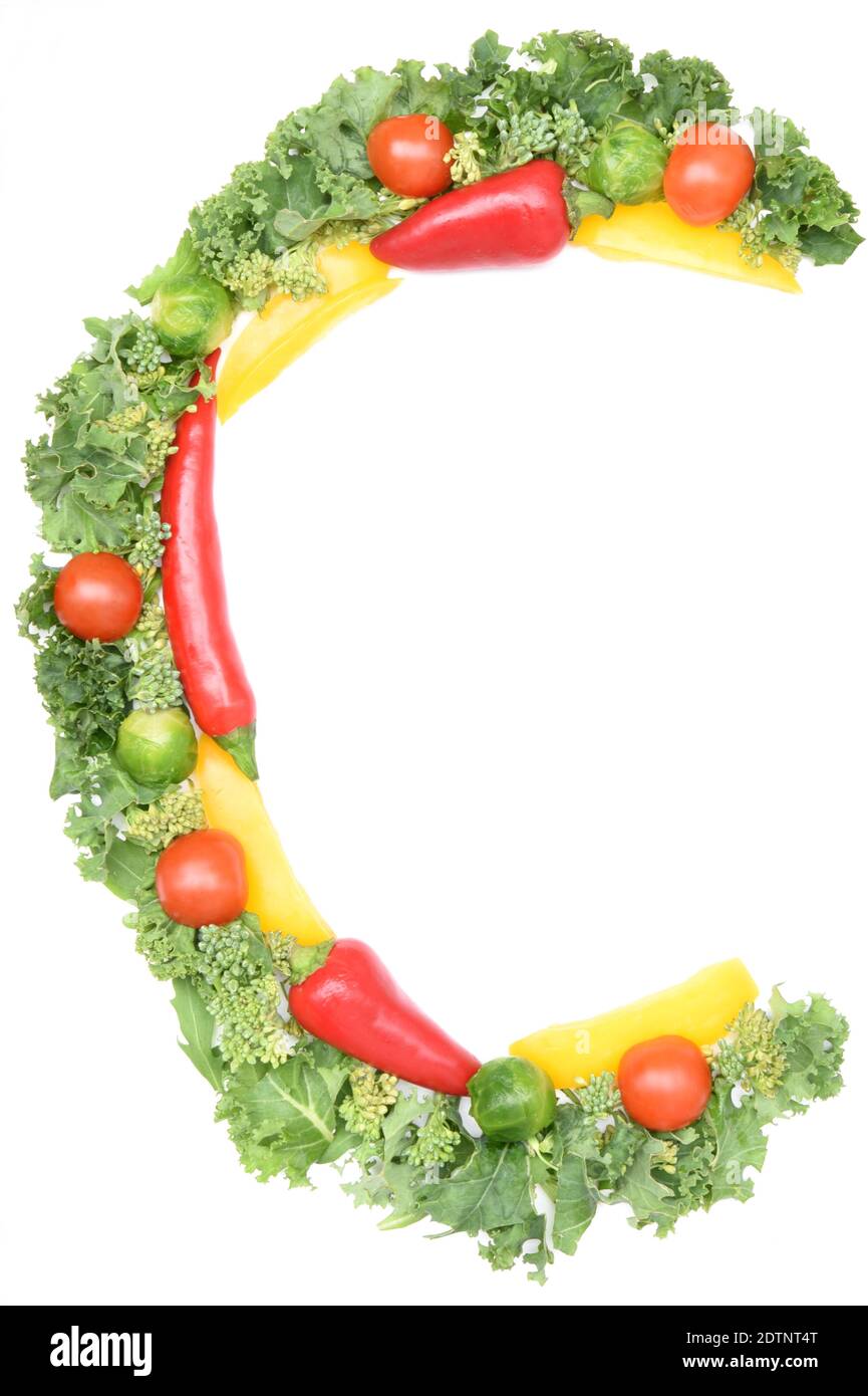 C shape letter made from vegetables high in vitamin C - kale, sweet peppers, chilli peppers, tomatoes and brussels sprouts on white background. Stock Photo