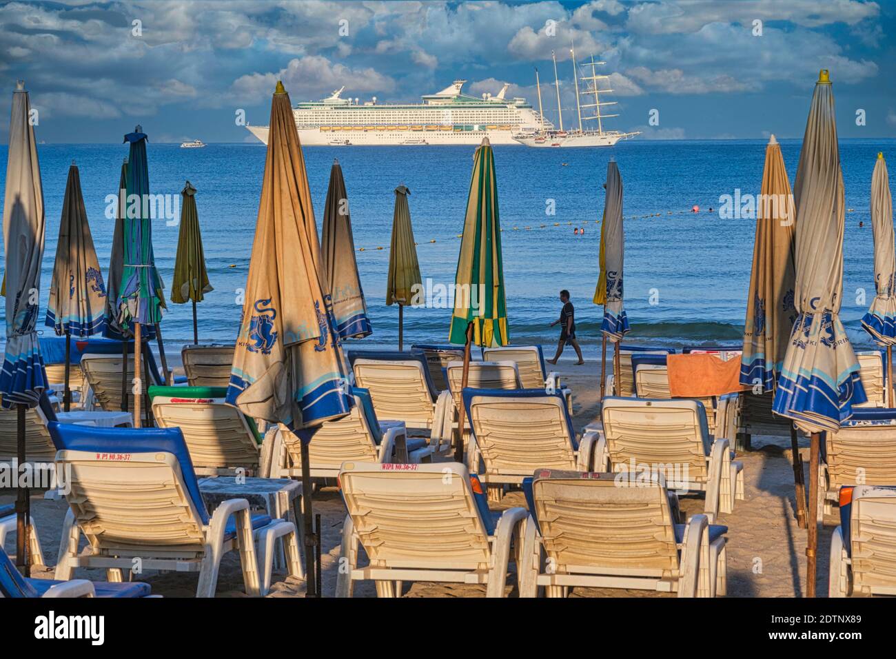 Early morning at Patong Beach, Phuket, Thailand, beach chairs still empty and with a cruise ship off-shore in the background Stock Photo