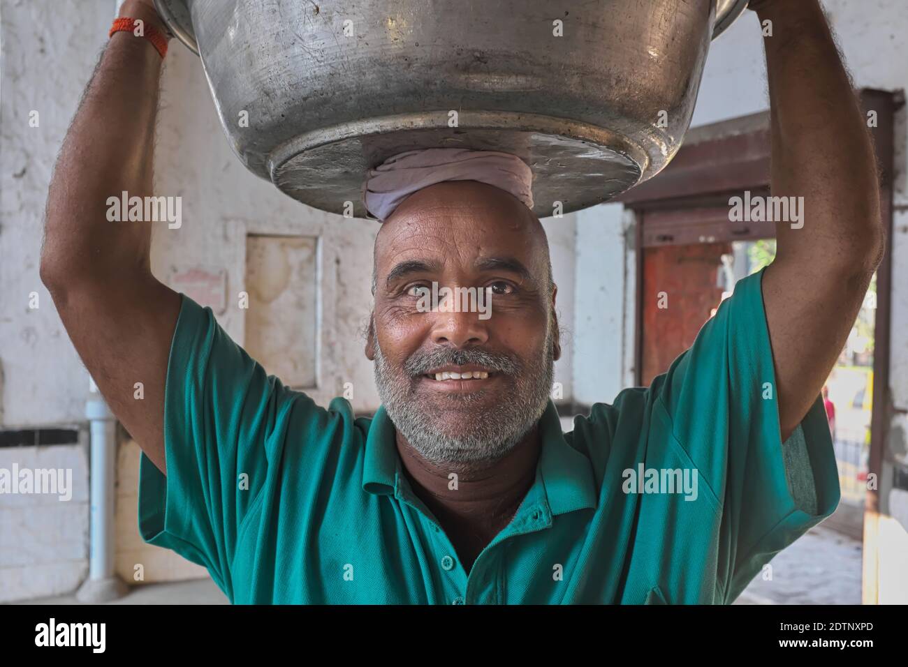 A friendly, smiling porter carrying fish from a fish market in Mumbai