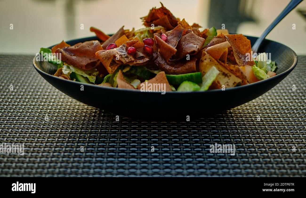 Fattoush (Lebanese salad) close up  image in a black plate . It is made with vegetables and crispy toasted flatbread, which soaks up the dressing Stock Photo
