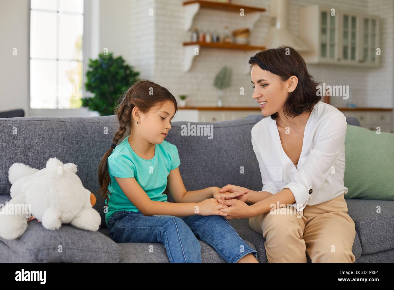 Sad girl having therapy session with child psychologist sitting on sofa in  privacy of her own home Stock Photo - Alamy