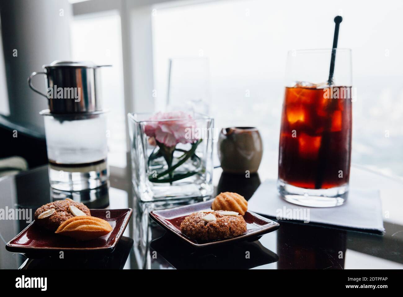 Hot and iced filtered Vietnamese coffee served with biscuits on the table. Stock Photo