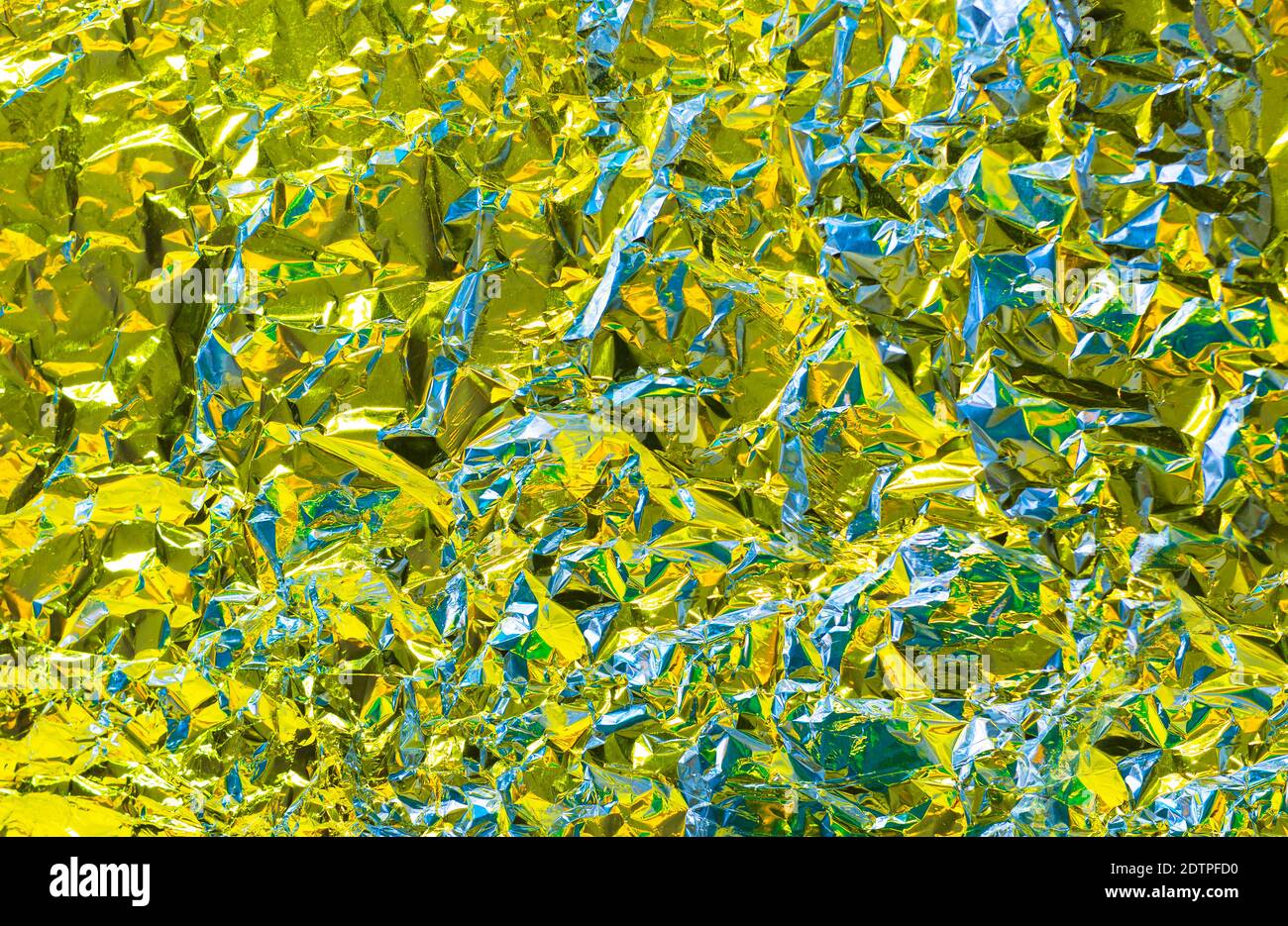 Metal chrome wrinkle texture with yellow tint and glance effect and crumpled structure with holographic iridescent effect with lime illuminating brigh Stock Photo