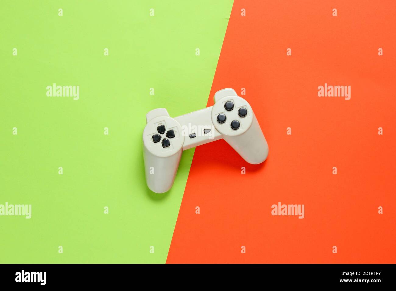 Retro style gamepad on green orange paper background, top view, minimalism Stock Photo