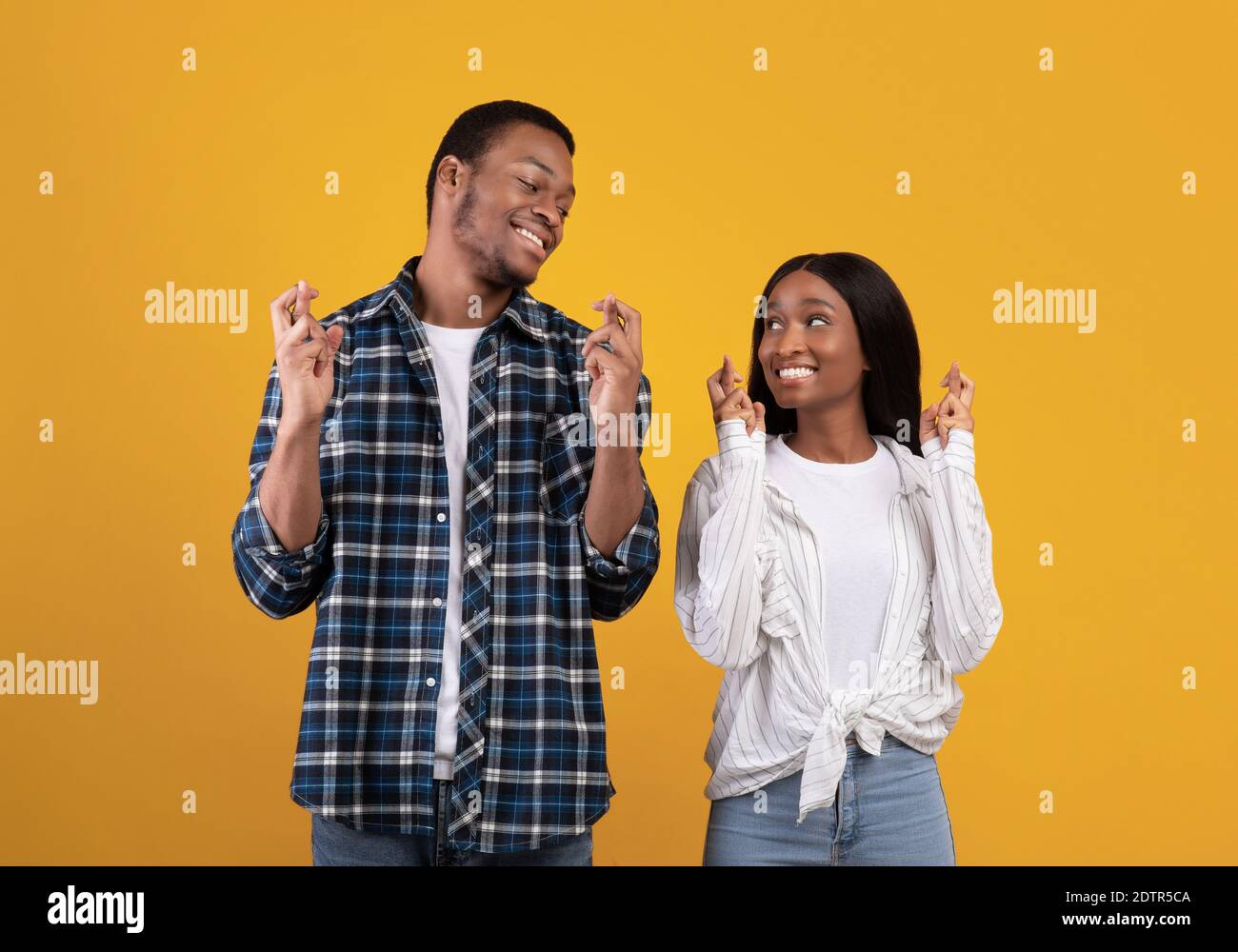Good luck, believe in superstition. Happy african american male and female in casual with fingers crossed Stock Photo