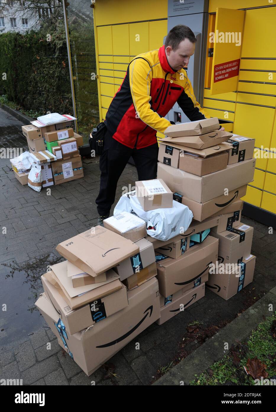22 December 2020, Mecklenburg-Western Pomerania, Rostock: In front of a DHL Packstation, Matthias Peters has stacked up parcel shipments that he has either taken from the station or has yet to put in. Last week, Swiss Post handled 61 million parcels, the largest volume in the company's history, which was around 20 percent more than in the strongest week of 2019. Photo: Bernd Wüstneck/dpa-Zentralbild/dpa - ATTENTION: Addresses on packages pixelated for privacy reasons Stock Photo