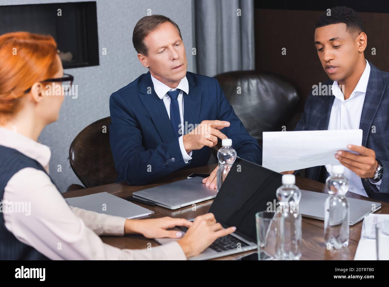 Executive pointing with finger at paper in hands of african american ...