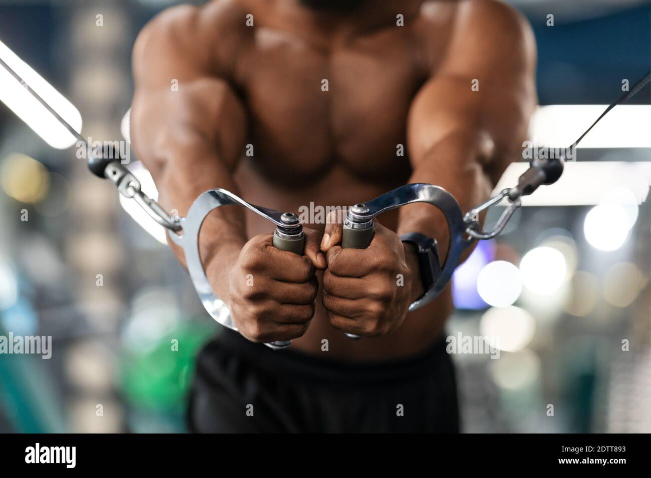 Unrecognizable black athlete training triceps on crossover exerciser in ...