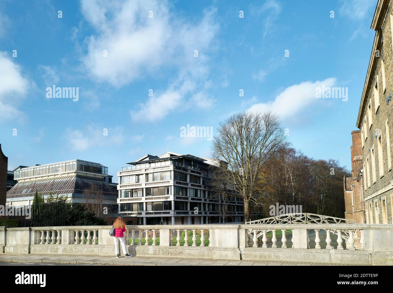 Female student stands next to the parapet of the road bridge over the river Cam outside Queens' college, Cambridge university, England. Stock Photo