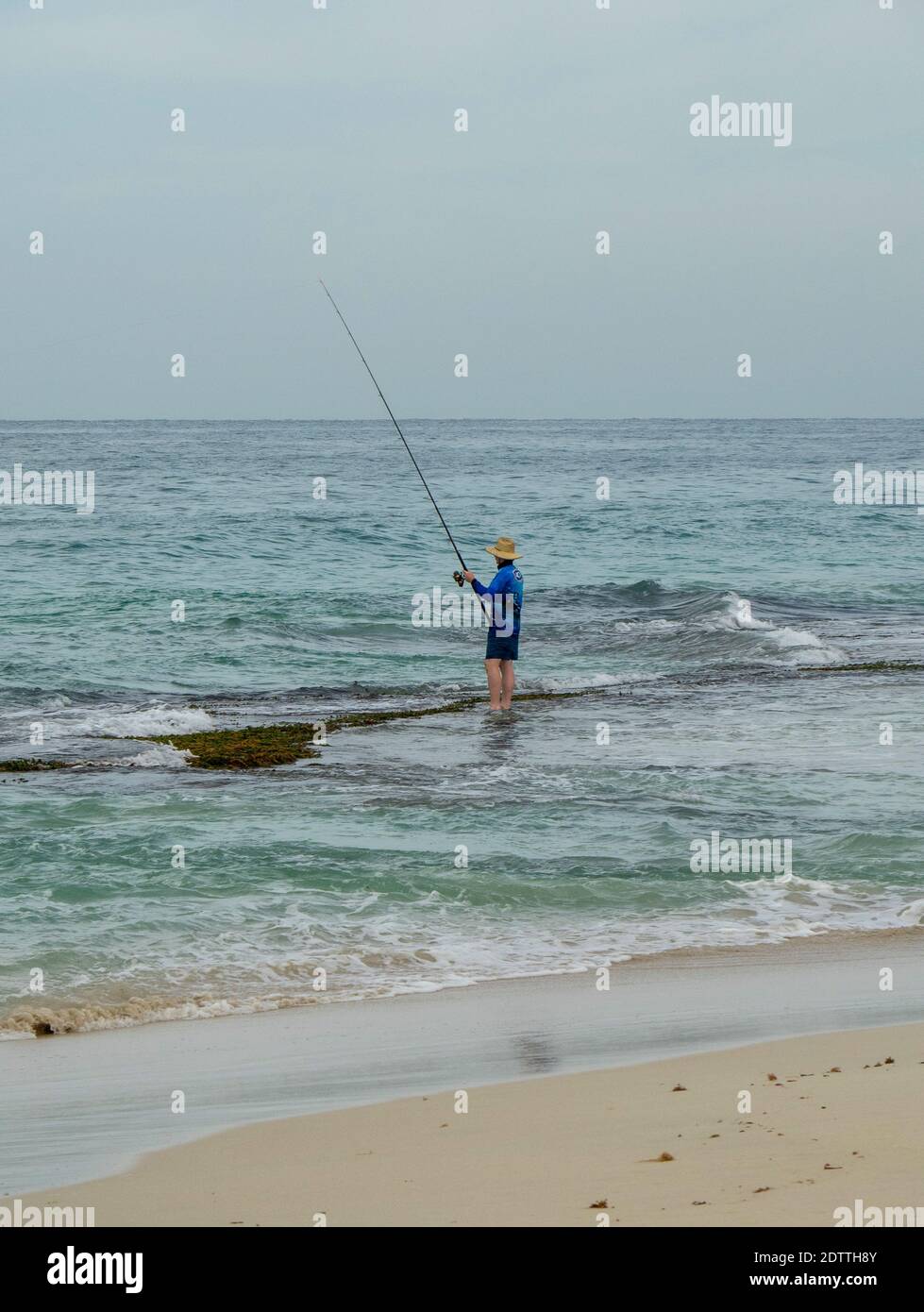 Man beach fishing with fishing rod standing on reef at Guilderton