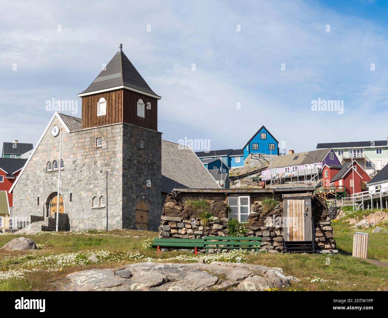 The church and a traditional peat - stone house, now part of the local museum. The town Uummannaq in the north of West Greenland, located on an island Stock Photo