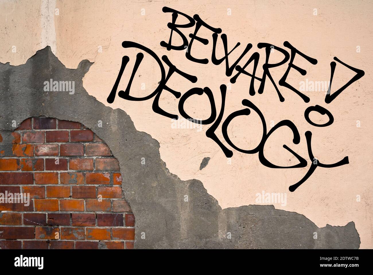 Handwritten graffiti Beware! Ideology sprayed on wall, anarchist ...