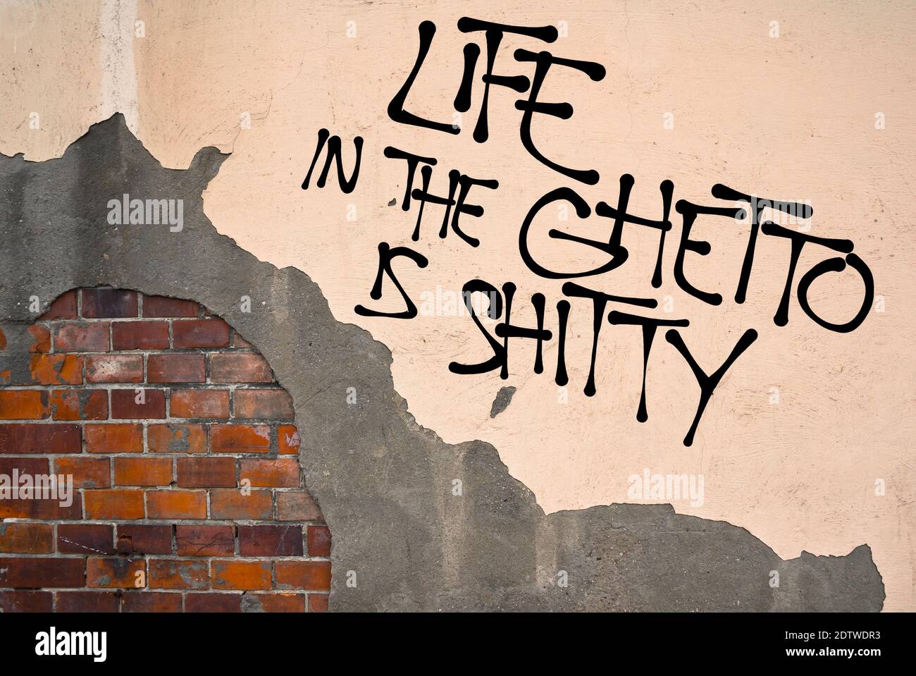 Life In The Ghetto Is Shitty - Handwritten graffiti sprayed on the wall, anarchist aesthetics. Protest against bad conditions in suburbs (criminality, Stock Photo