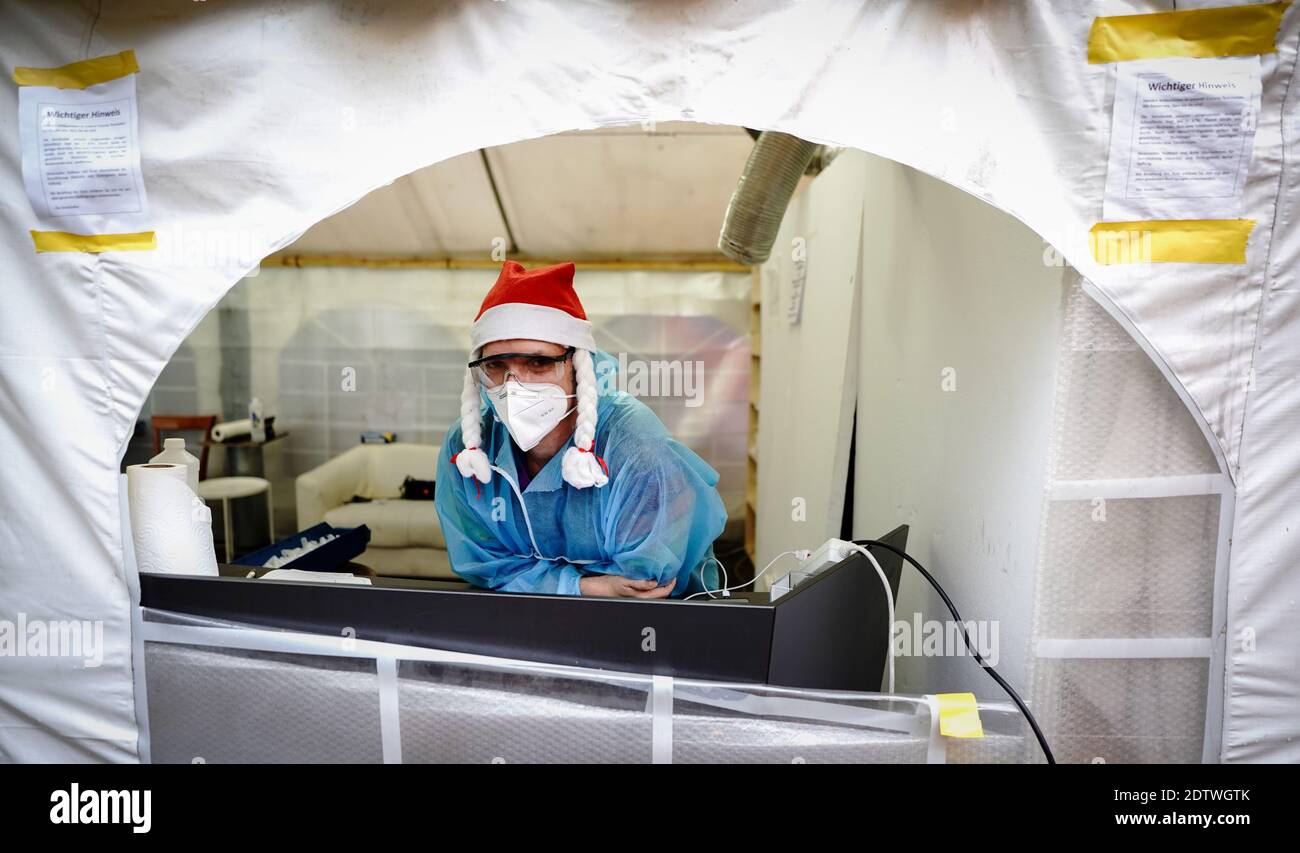 Berlin, Germany. 22nd Dec, 2020. An employee of the Corona Test Center at  the Kitkat Club looks out of the tent in a Santa hat and protective  clothing. During Christmas and New
