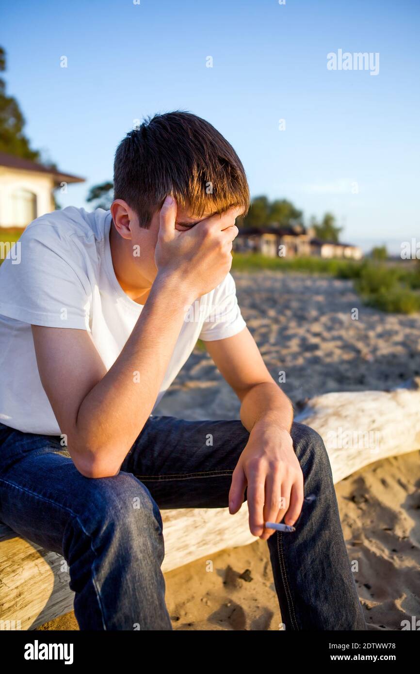 Sad Young Man sit on the Log on the Nature Background Stock Photo