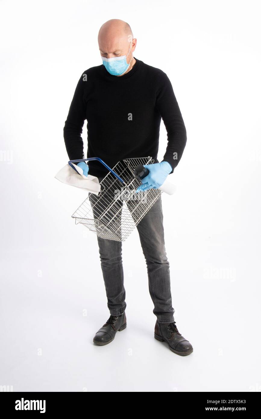Man with mouth protection and hand gloves cleaning a shopping basket, isolated on white background Stock Photo