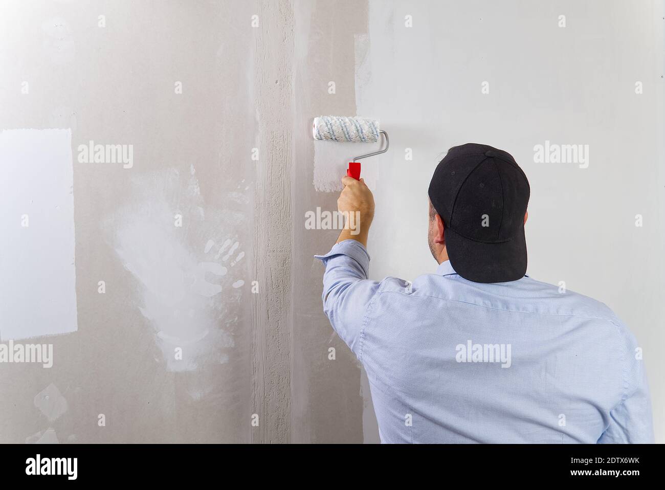 Painting a drywall by painting roller and white latex color Stock Photo