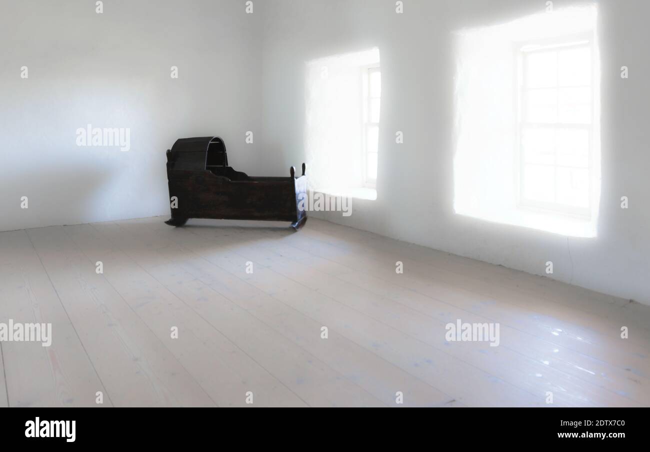 Vintage wooden rocking baby bed in the empty bright room with two windows Stock Photo