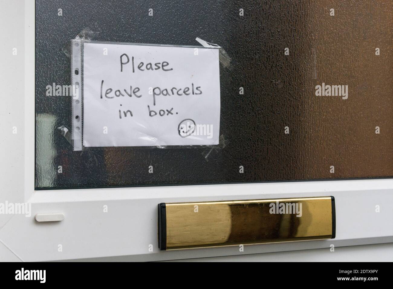 Handwritten covid sign on house door, asking for deliveries to be left in receiving box outside the front door. For life under Covid UK, covid safety. Stock Photo