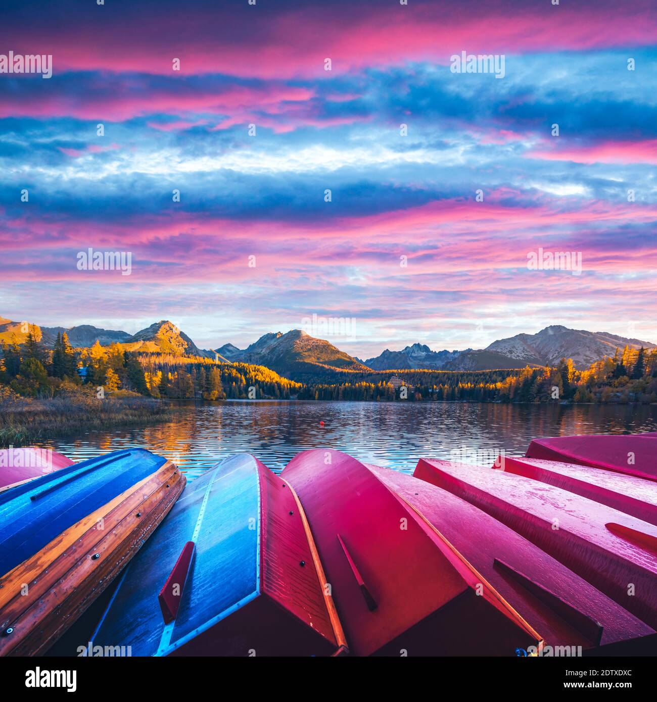 Picturesque autumn view of lake Strbske pleso in High Tatras National Park, Slovakia. Row of red wooden boats and high mountains on background. Landscape photography Stock Photo