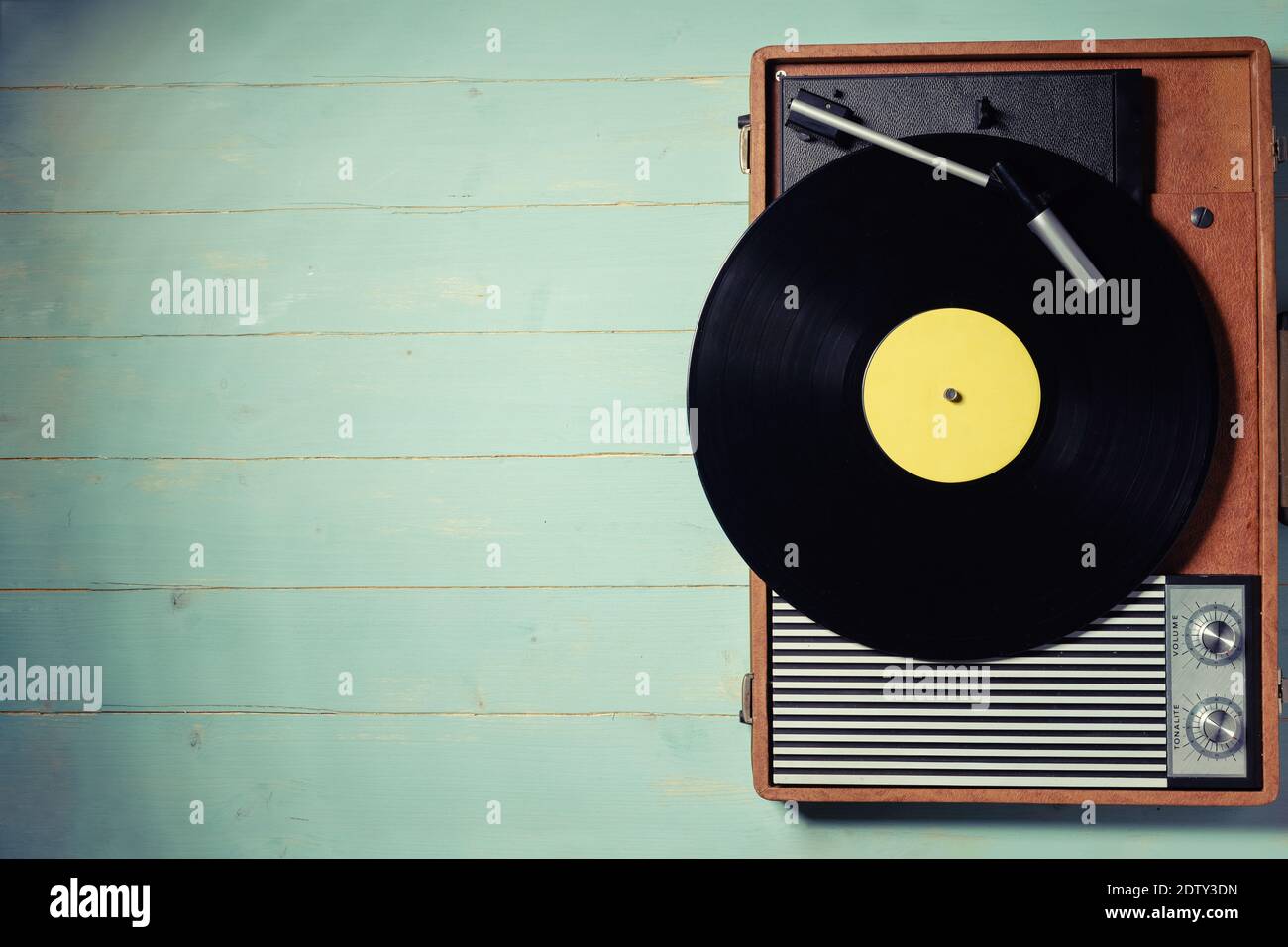Vintage turntable with a vinyl record on green wooden table, top view ...