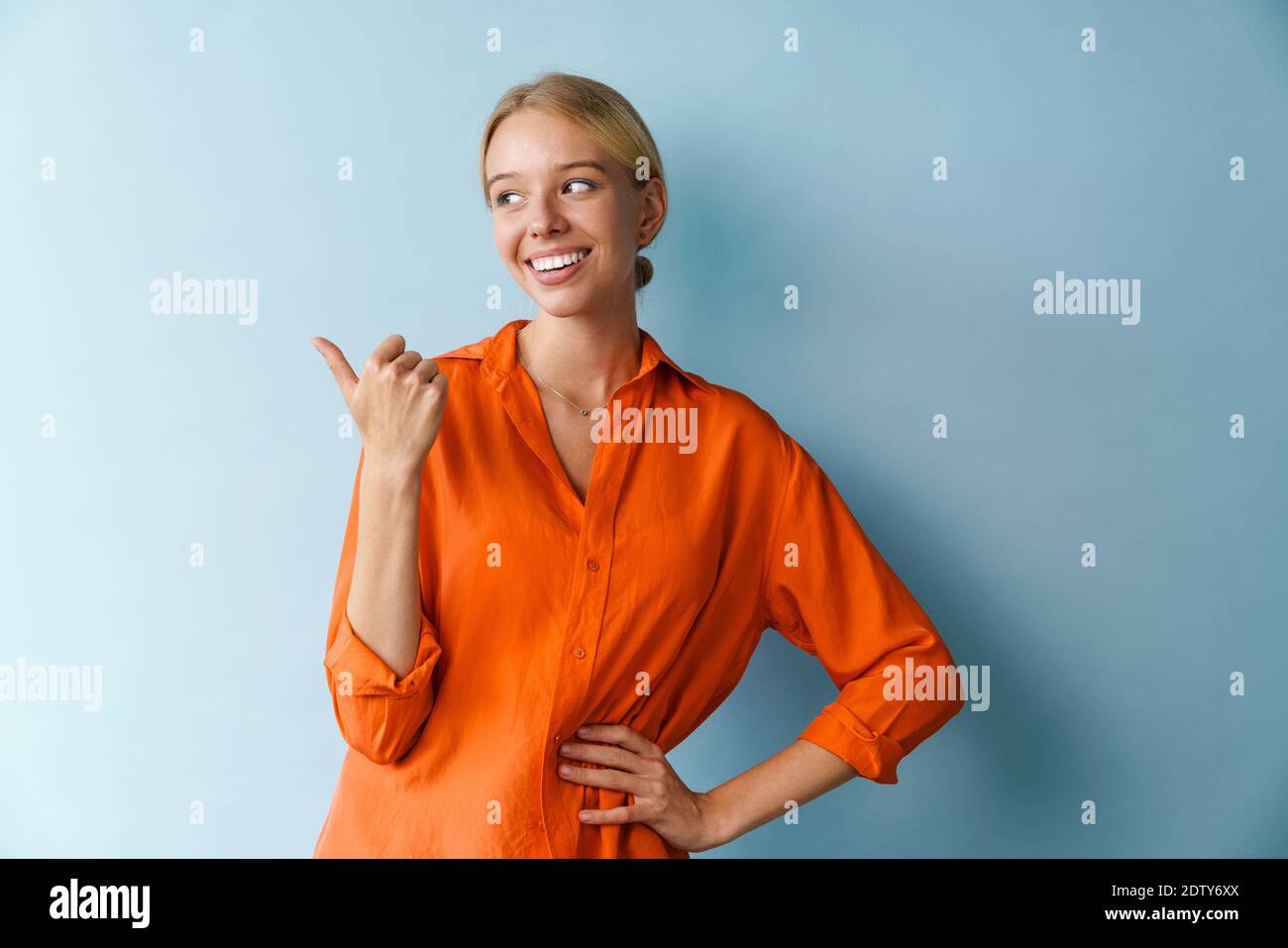 Joyful beautiful girl pointing finger aside and smiling isolated over ...