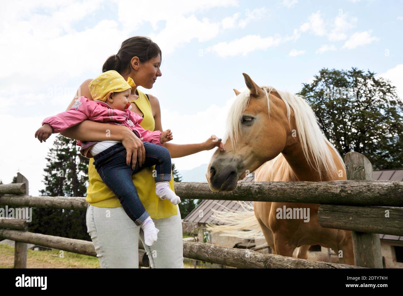 Mom with her daughter having fun at farm ranch and meeting a horse
