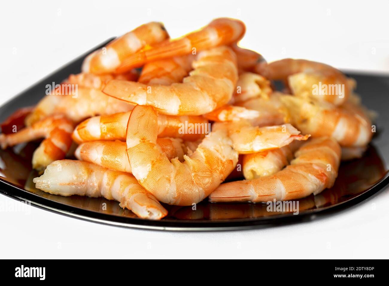 Peeled shrimp on black plate on white background Stock Photo