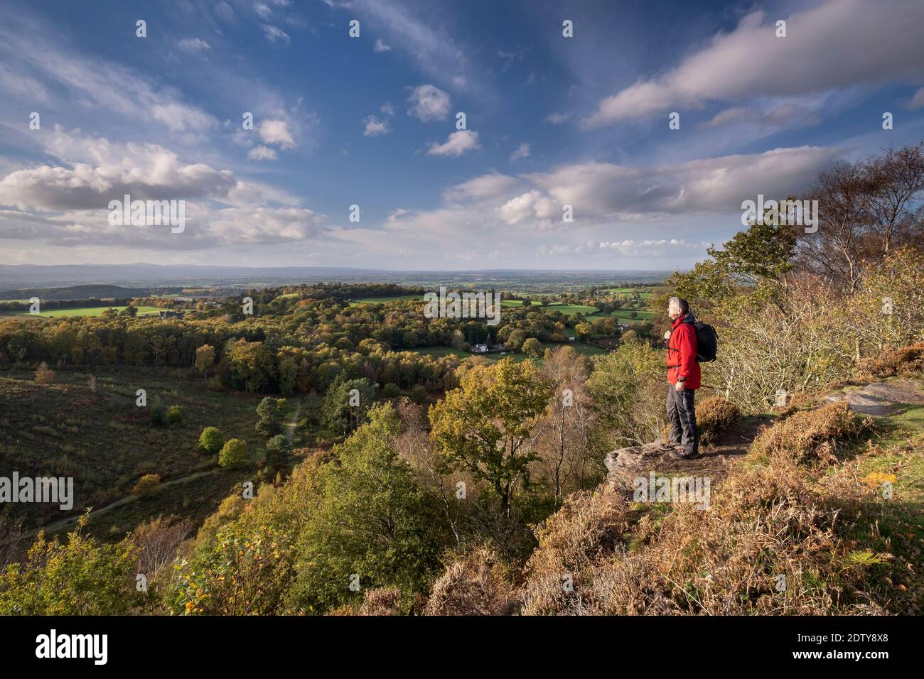 Walker enjoying the view over the Cheshire Plain in autumn from Maiden Castle, Bickerton Hill, Cheshire, England, UK Stock Photo