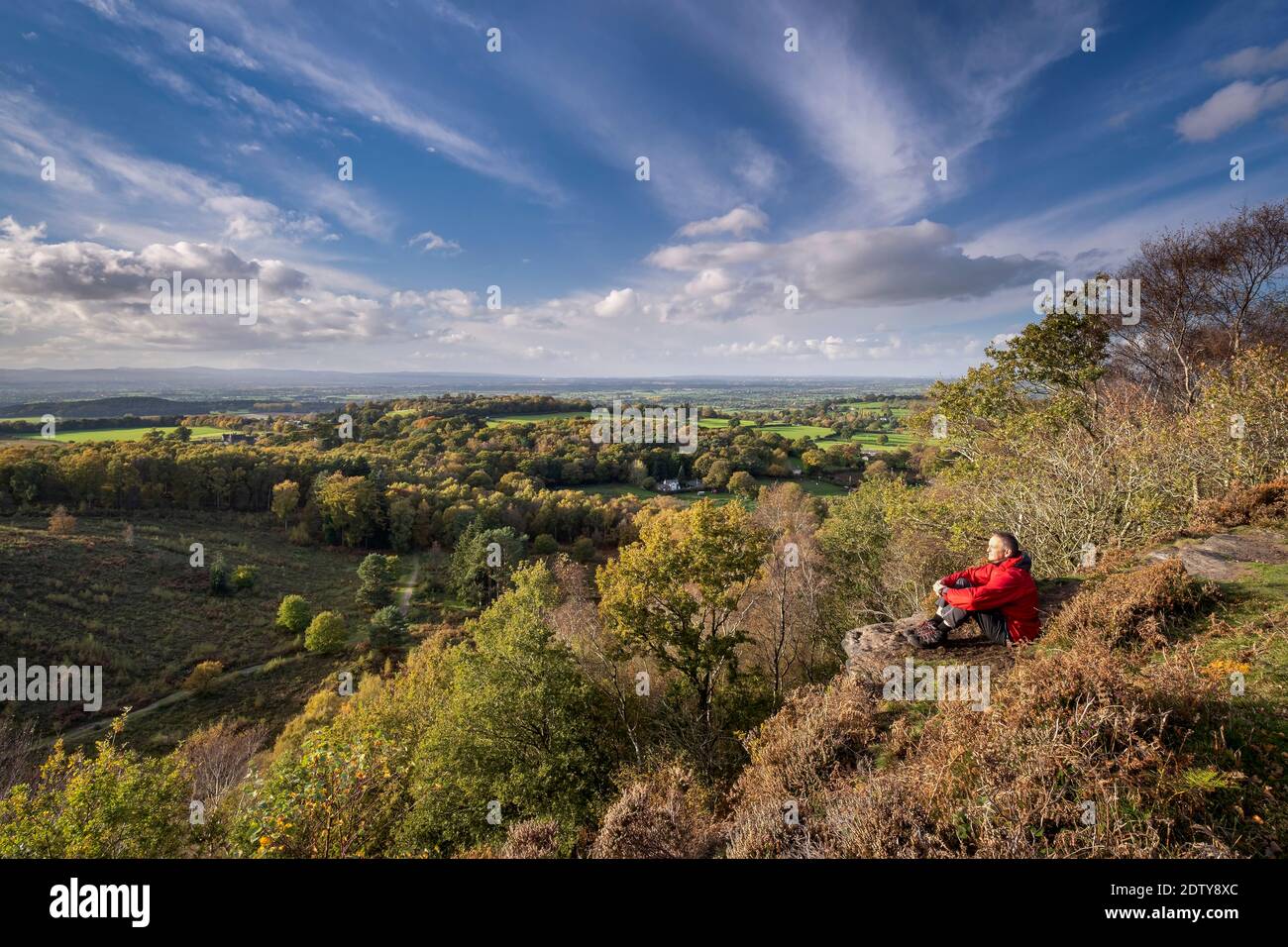 Walker enjoying the view over the Cheshire Plain in autumn from Maiden Castle, Bickerton Hill, Cheshire, England, UK Stock Photo