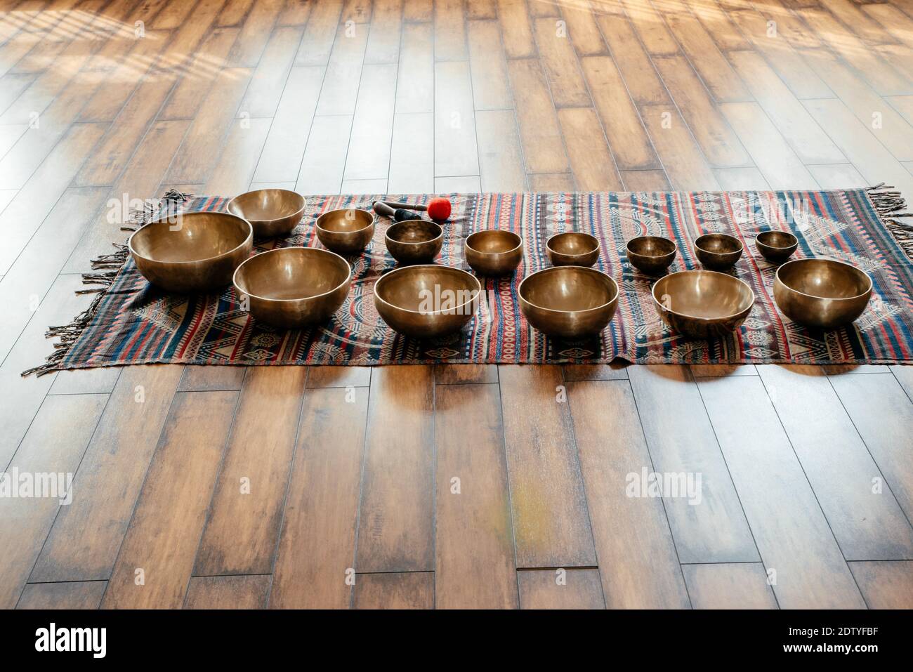 Many Tibetan handcrafted singing bowls on the floor in yoga class, sound therapy concept Stock Photo