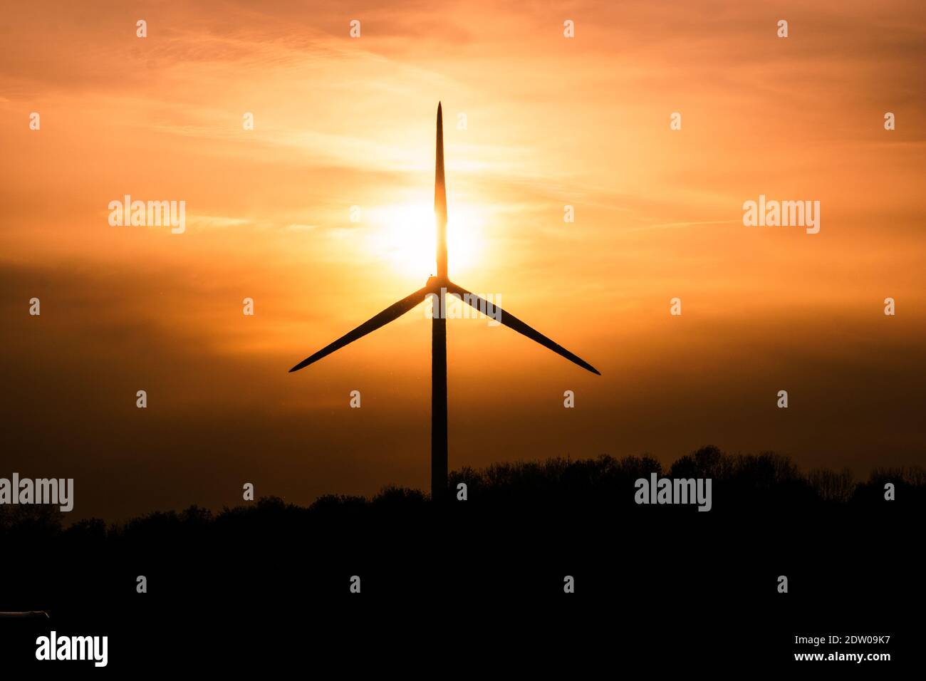 single wind turbine silhouettes at cloudy golden sunset Stock Photo
