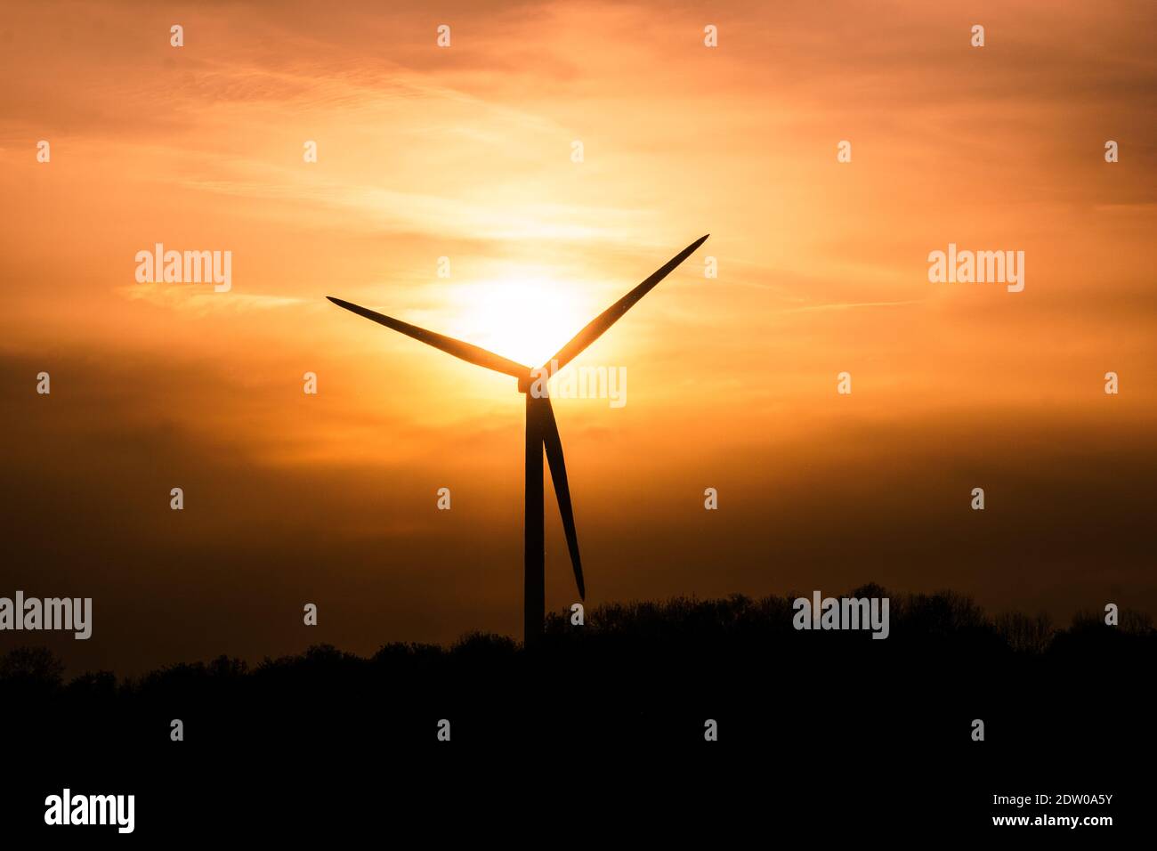 single wind turbine silhouettes at cloudy golden sunset Stock Photo