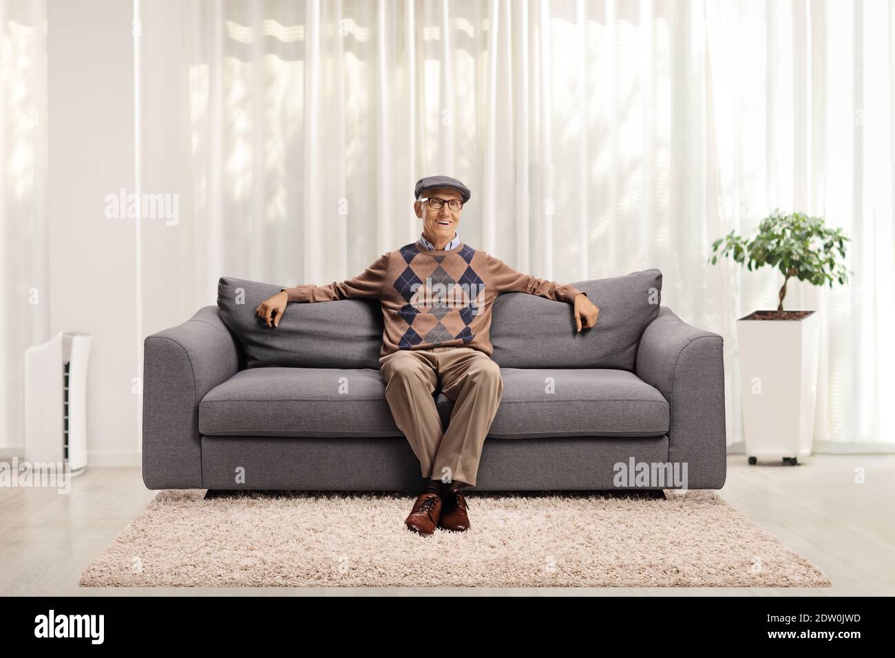 Smiling mature man sitting on a sofa at home Stock Photo - Alamy