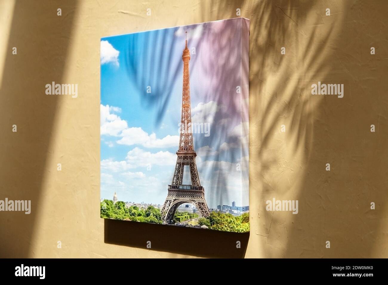 Canvas print with gellery wrap on surface with sunlight and shadows of leaves. Photo printed on canvas. Stretched photography with image of Eiffel Tow Stock Photo