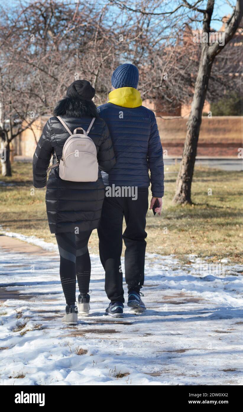 A young couple visiting Santa Fe, New Mexico, in the winter walk along a sidewalk in the historic city. Stock Photo