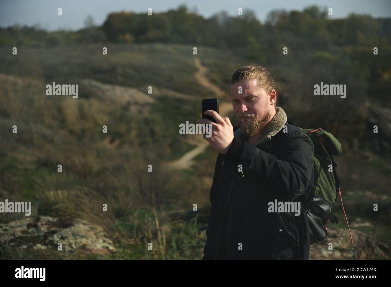 Hiker using compass on smart phone in forest. Walkway on background Stock Photo
