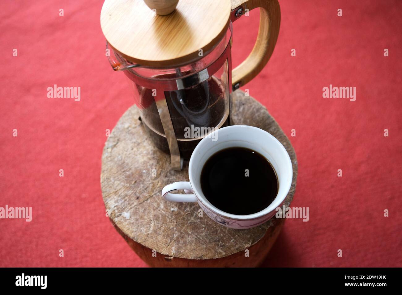 A pot of coffee and french press on the cut wooden with red carpet background. Stock Photo