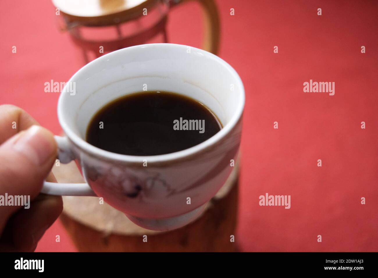 A pot of coffee holding by hand and french press and red carpet background. Stock Photo