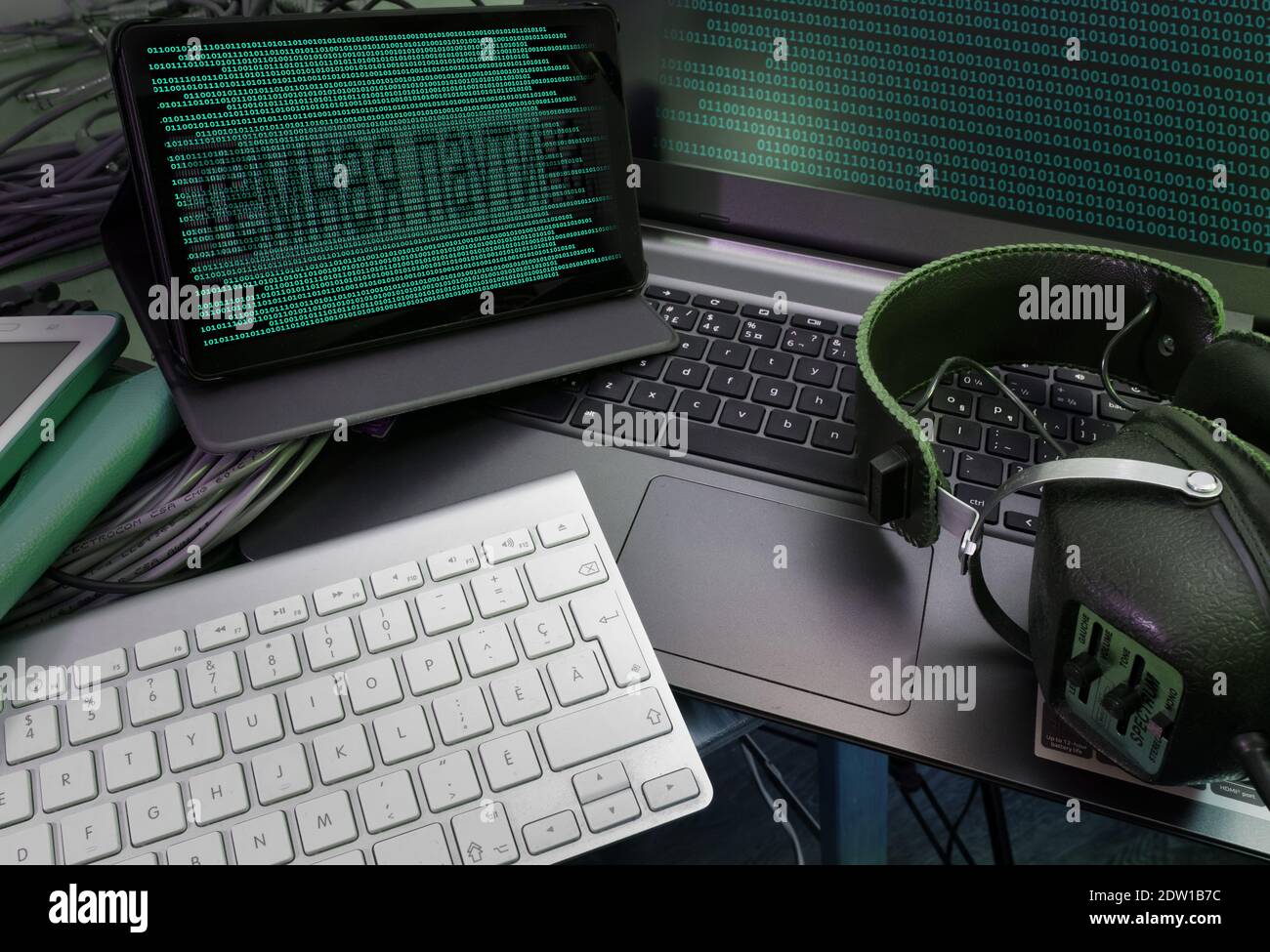 Binary codes on the screens of the computer and tablette, a headphone as well. Russian script meaning 'cyber attack'.. Stock Photo