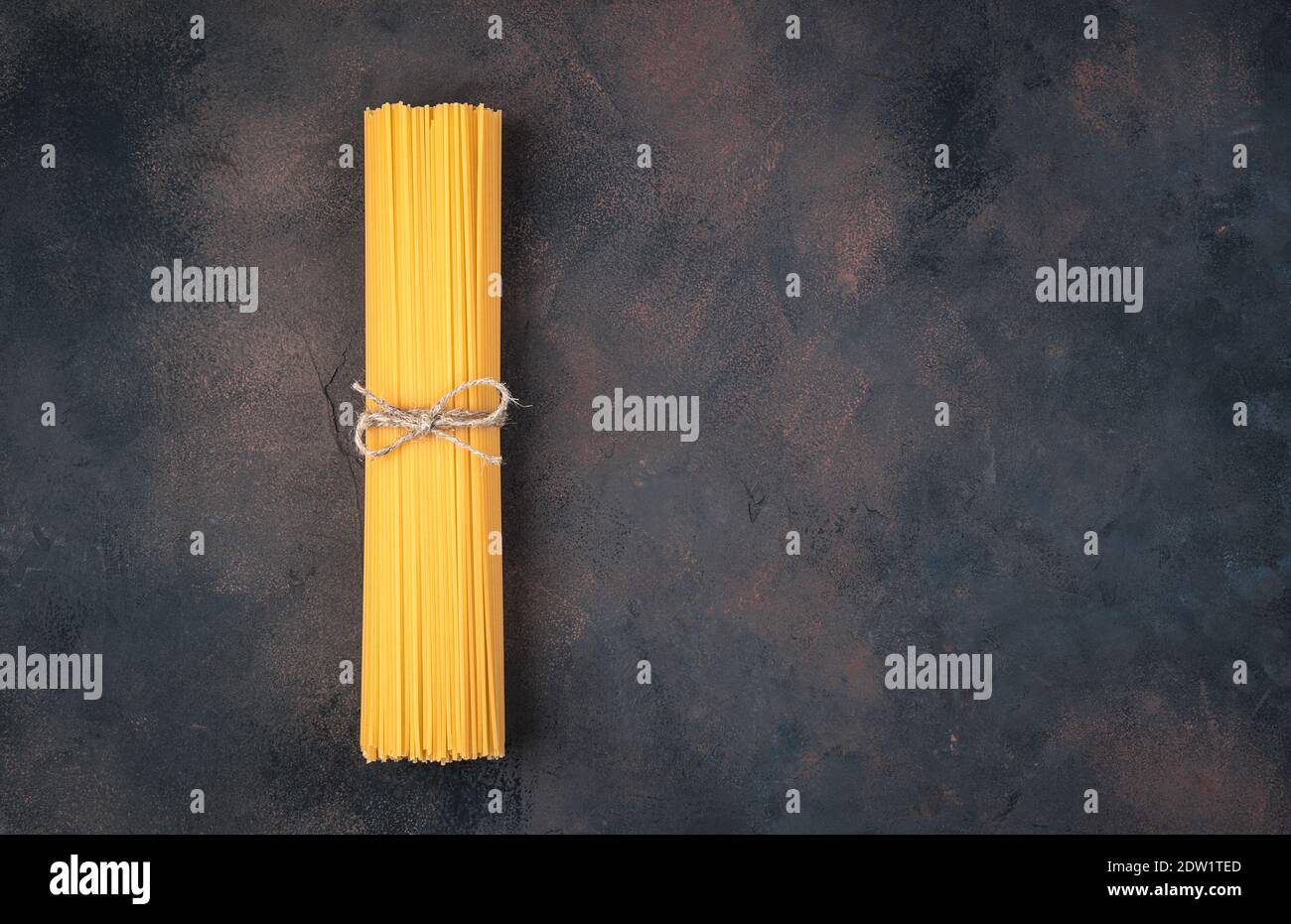 Spaghetti tied with thread on a brown concrete background Stock Photo ...
