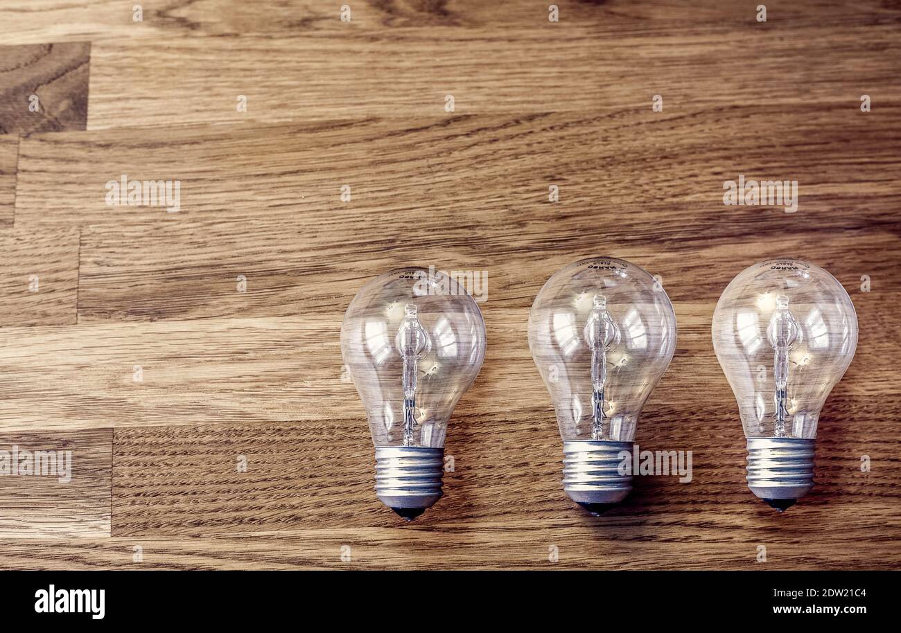 Three light bulbs on wooden table. Concept for idea, thinking, problem solving Stock Photo