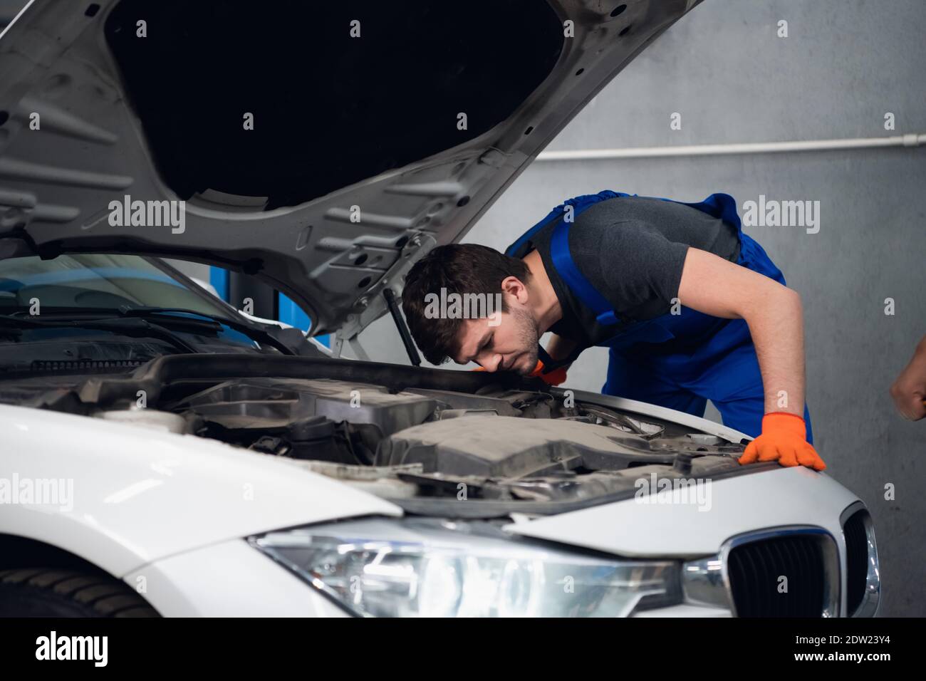 Finger Rocker Car Repairman rocker shows a gesture with his fingers. He is standing next ...